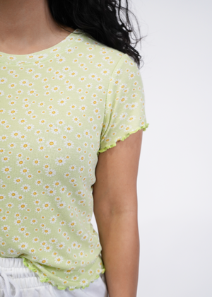 
                  
                    Close up of model wearing brandy baby hem tee in lime green daisy
                  
                
