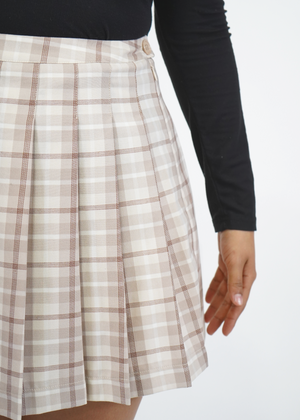
                  
                    Close up of model wearing Olivia pleated skirt in Iced Coffee Plaid
                  
                